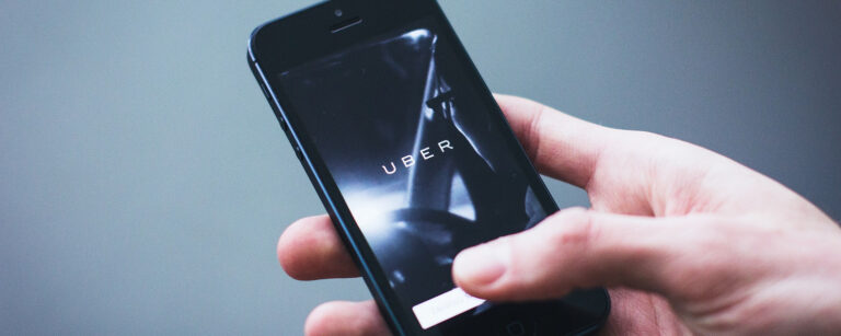 Photograph of man using the Uber App on a blue background.